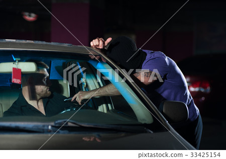 Aggressive thief pointing a gun at auto owner 33425154
