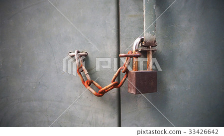 Old rust lock key with chain on grey cement wall. 33426642