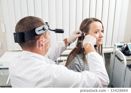 ENT physician looking into patient's ear with an 33428664