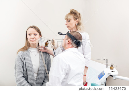 ENT physician looking into patient's ear with an 33428670