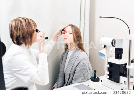Senior female optometrist examining young woman's Senior female optometrist examining young woman's 33428683
