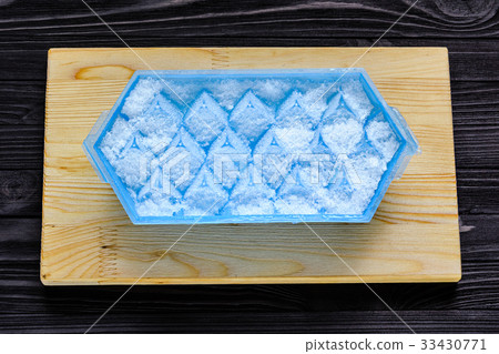 A blue plastic ice cube tray with frost on it 33430771