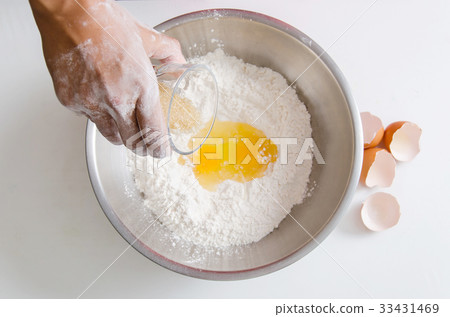 Hand pouring sugar and egg yolk mixing with flour Hand pouring sugar and egg yolk mixing with flour 33431469
