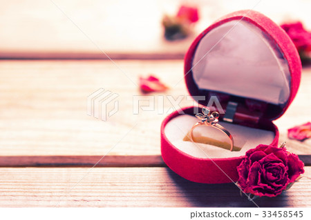 Golden engagement ring in a heart shaped box 33458545