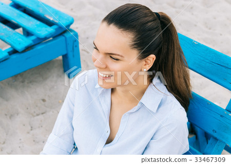 Cute young brunette woman sitting on a bench 33467309