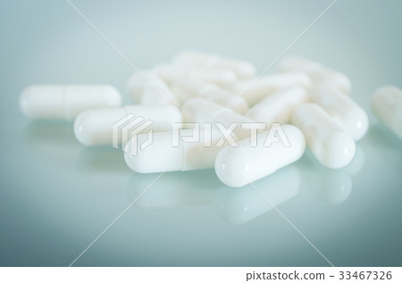 White medical capsules lie on the mirror surface 33467326
