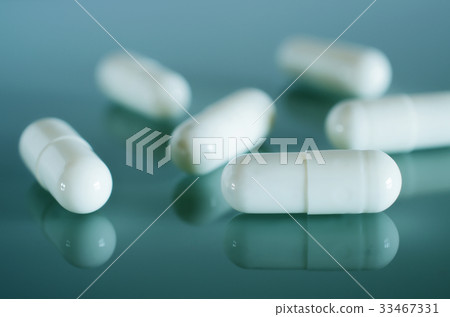 White medical capsules lie on the mirror surface 33467331