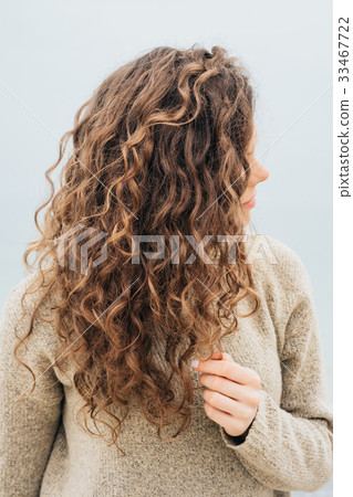 Curly brunette in a sweater on the coast Curly brunette in a sweater on the coast 33467722