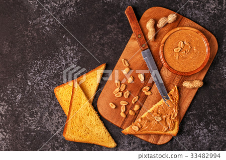 Bowl of peanut butter on wooden board. 33482994