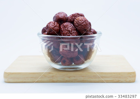 Red jujube on glass cup over wooden board 33483297