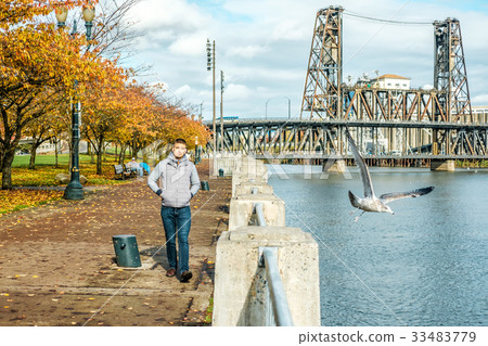 Man walking along the riverwalk in Portland city at autumn 33483779