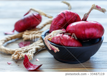 Sweet red onions in a wooden bowl. 33487119