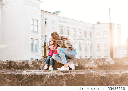 Mom and daughter sit together on the fence Mom and daughter sit together on the fence 33487518