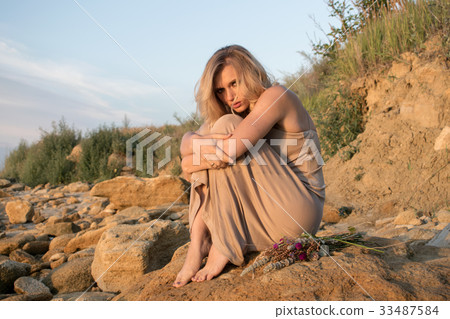 Young barefoot woman sitting on stones Young barefoot woman sitting on stones 33487584
