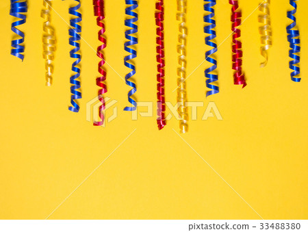 Border of colored festive ribbons on a yellow background. Gift scenery. 33488380