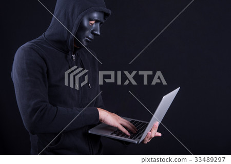 Male hacker with black mask carrying laptop 33489297