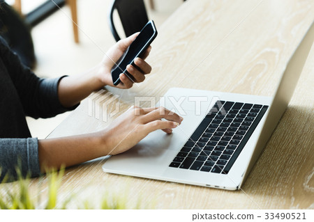 woman use laptop and smart phone on desk 33490521