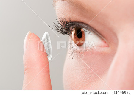 Woman inserting a contact lens in eye. 33496952