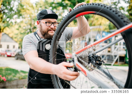 Bicycle repairman works with bike wheel 33506165