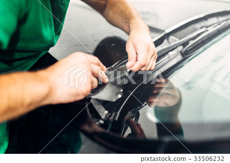 Worker hands installs car paint protection film 33506232