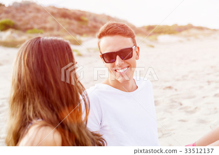 Romantic young couple sitting on the beach Romantic young couple sitting on the beach 33512137