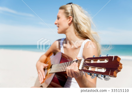 Beautiful young woman playing guitar on beach Beautiful young woman playing guitar on beach 33515110