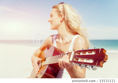 Beautiful young woman playing guitar on beach Beautiful young woman playing guitar on beach 33515111