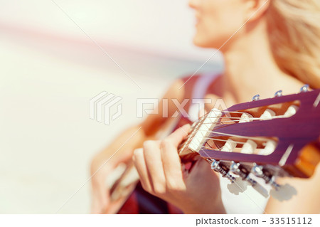 Beautiful young woman playing guitar on beach Beautiful young woman playing guitar on beach 33515112