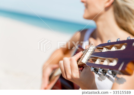 Beautiful young woman playing guitar on beach Beautiful young woman playing guitar on beach 33515589