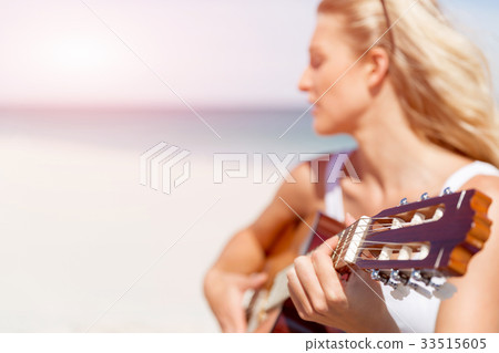 Beautiful young woman playing guitar on beach Beautiful young woman playing guitar on beach 33515605