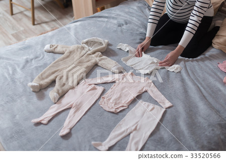 Baby's clothes laid out on bed, natural light. 33520566