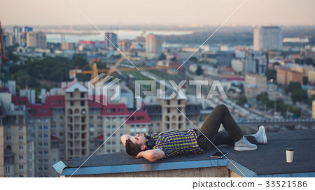 Man is listening to music on roof. Man is listening to music on roof. 33521586