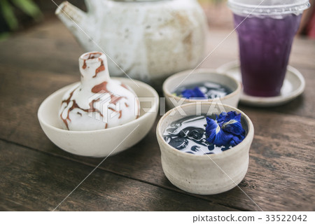 Clay pot of iced butterfly pea tea on wooden table 33522042