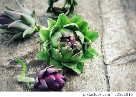 Green and purple artichokes on rustic wooden Green and purple artichokes on rustic wooden 33531810