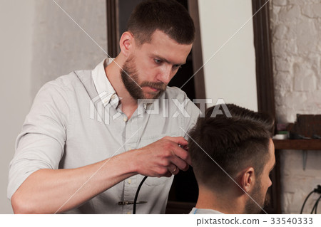 Young handsome barber making haircut of attractive Young handsome barber making haircut of attractive 33540333