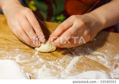 A woman is making dough patties on table flour A woman is making dough patties on table flour 33540503