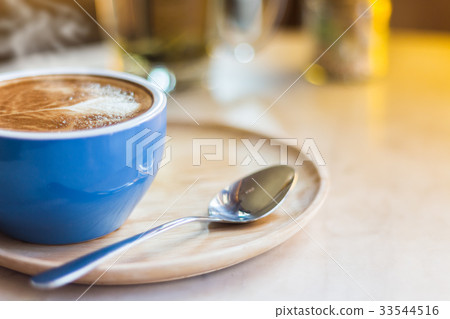 Close up coffee cup with steam on table in cafe. 33544516