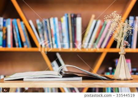 Reading book on wood table against shelf. Reading book on wood table against shelf. 33544519