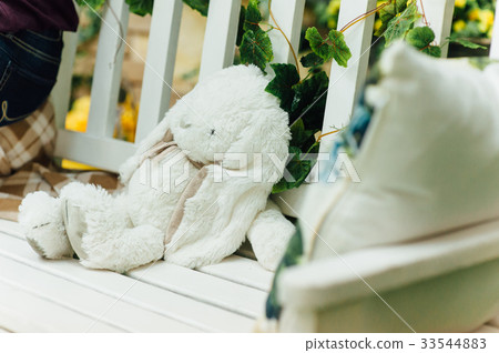 White toy rabbit lies on  bench 33544883