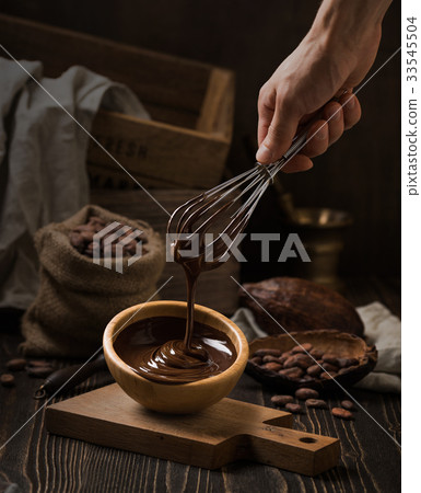 Dark still life with melted chocolate in wooden 33545504