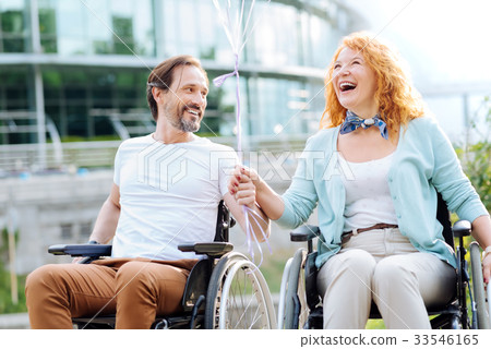 Joyful senior wheelchaired couple enjoying walk in 33546165