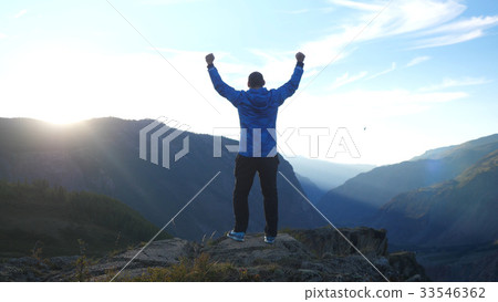 Success young man raising his hands high on top of 33546362