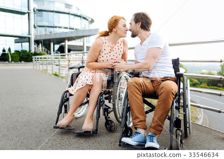Pleasant disabled senior couple kissing outdoors Pleasant disabled senior couple kissing outdoors 33546634
