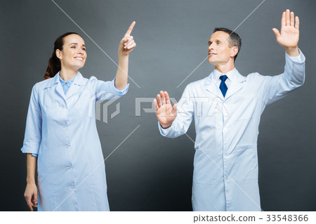 Cheerful medical coworkers touching invisible Cheerful medical coworkers touching invisible 33548366