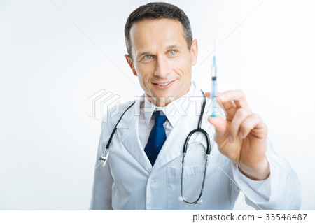 Satisfied doctor checking syringe before injection Satisfied doctor checking syringe before injection 33548487