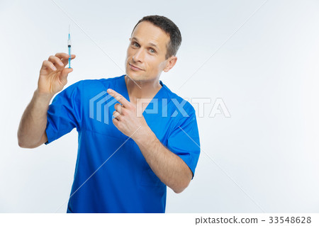 Positive minded physician pointing toward syringe Positive minded physician pointing toward syringe 33548628