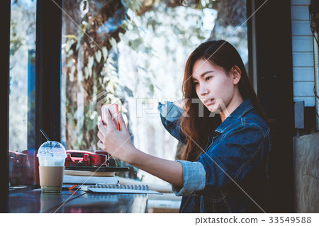 Teenage using cellphone with selfie in cafe. Teenage using cellphone with selfie in cafe. 33549588