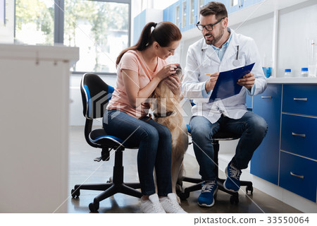 Charming female looking at teeth of her dog Charming female looking at teeth of her dog 33550064