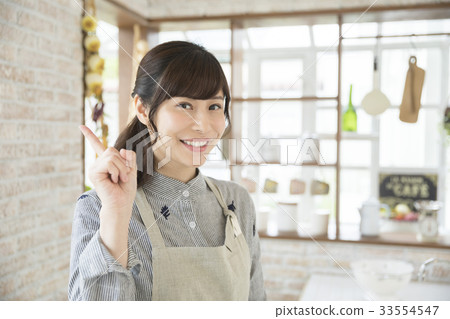 Housewife showing forefinger in the kitchen 33554547