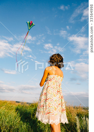 Girl playing with kite in field 33564998